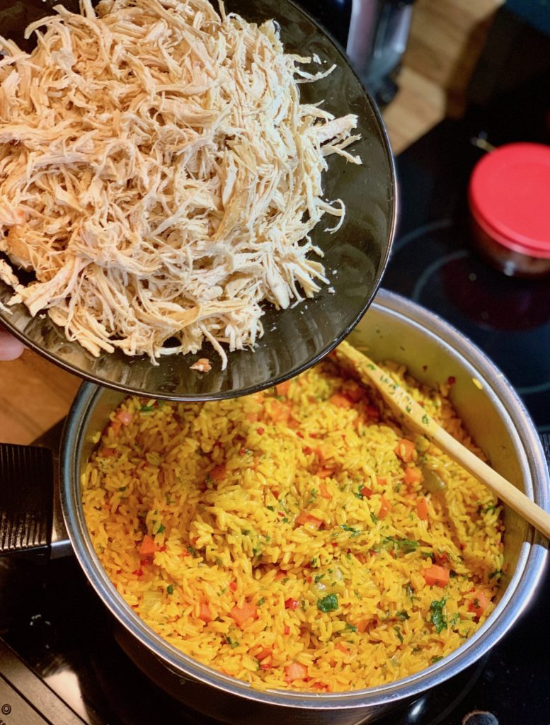 Adding shredded chicken to arroz con pollo recipe